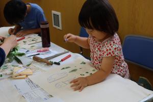 ランチョンマットに布描きクレヨンでお絵描きする子ども