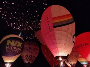 色とりどりの気球と遊水池の夜空に花火が上がる