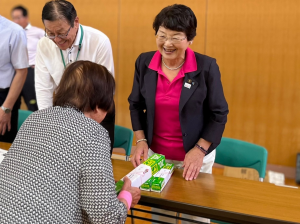 交流会で参加者に景品のラップを手渡しする市長