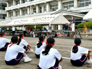 校庭に座る生徒の前でご挨拶