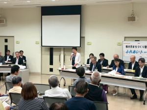 集まった市民の前でマイクを持ち行政報告をする