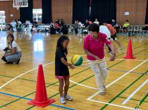 競技に急遽参加、二本の棒でバレーボールを落とさず運べるかな