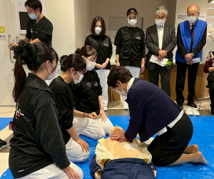 市長が人形の胸に両手をあて心臓マッサージの指導をうける