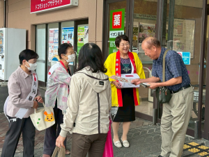 募金箱を首に下げスーパーの出入り口で募金を市民に呼びかけ