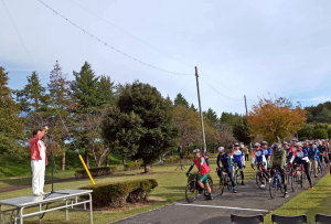 色とりどりのユニホームの選手がロードサイクルにまたがり、市長のスタートの合図を待つ