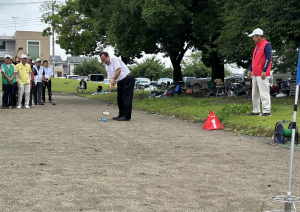 大勢の選手の前で青いボールで始球式