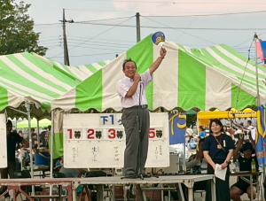 うちわを左手で持ち上げにこやかに挨拶