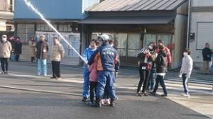市長と小学生と消防士で消防ホースを持ち放水訓練