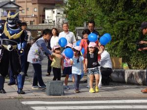 市長から渡された青い風船を手に持ち横断歩道を歩く園児たち