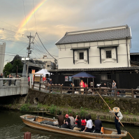挨拶の時、巴波川沿いの蔵をバックに空には虹が、巴波川には船頭が船をはしらせ