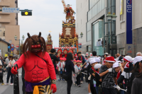 大通りに市内の小学生が山車を引き祭りを賑やかにしている