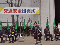 山車会館前で緑色の旗が一列に並ぶ前で出発式