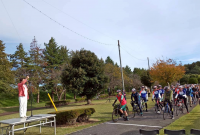 色とりどりのユニホームの選手がロードサイクルにまたがり、市長のスタートの合図を待つ